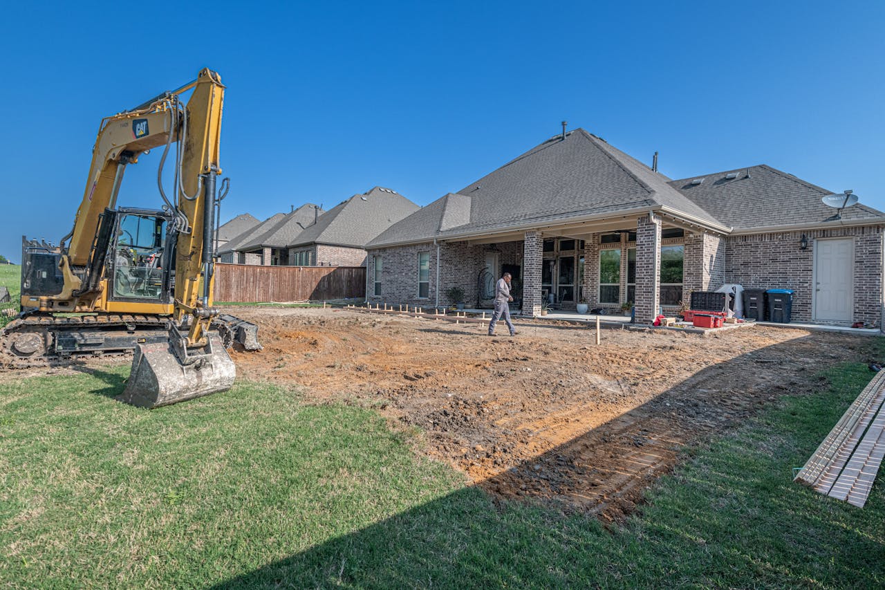 A construction site for a new patio in a Texas backyard with heavy machinery.
