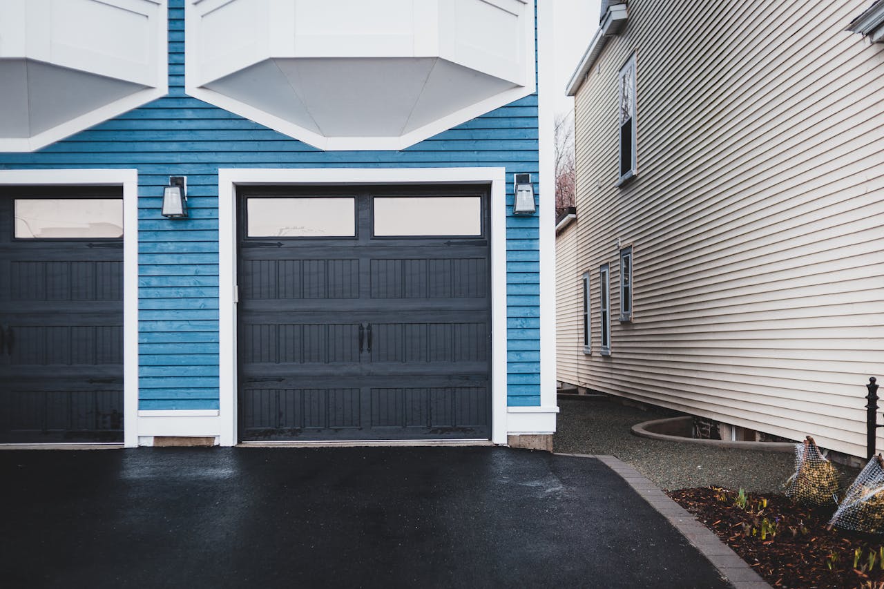 Elegant urban house exterior with blue facade and stylish garage doors.